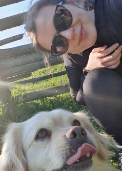 Picture of a woman smiling and a dog, both looking at the camera